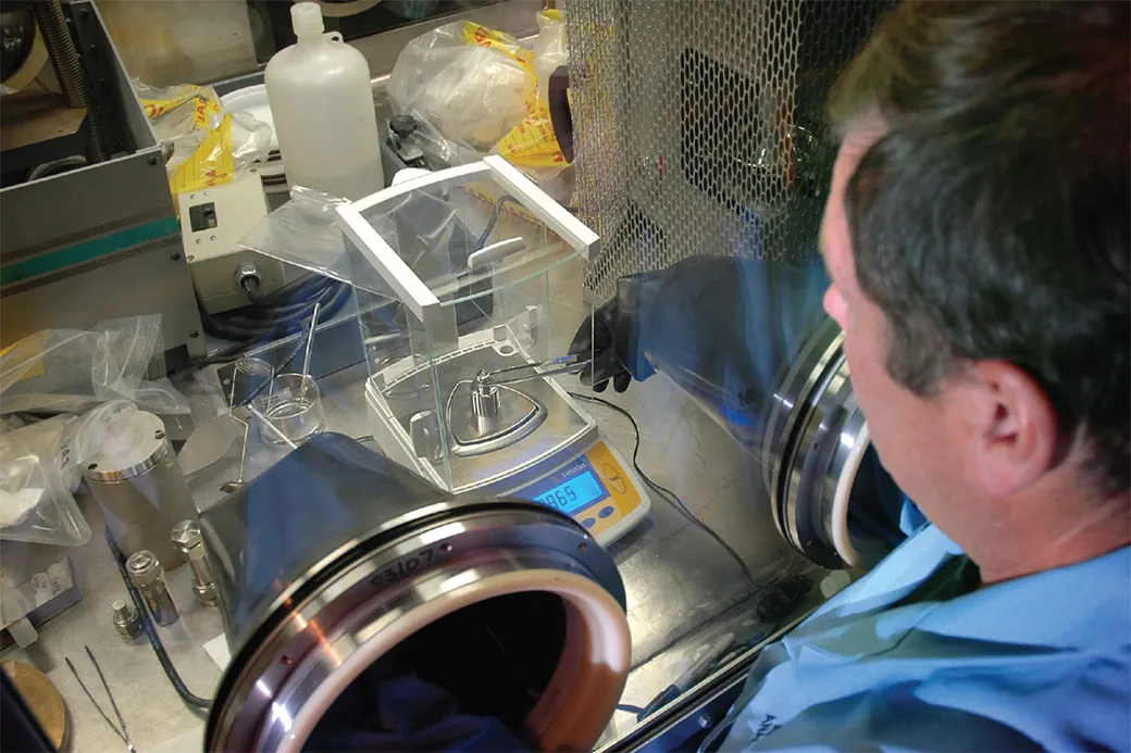 A technician handling a sample inside a glove box atmosphere