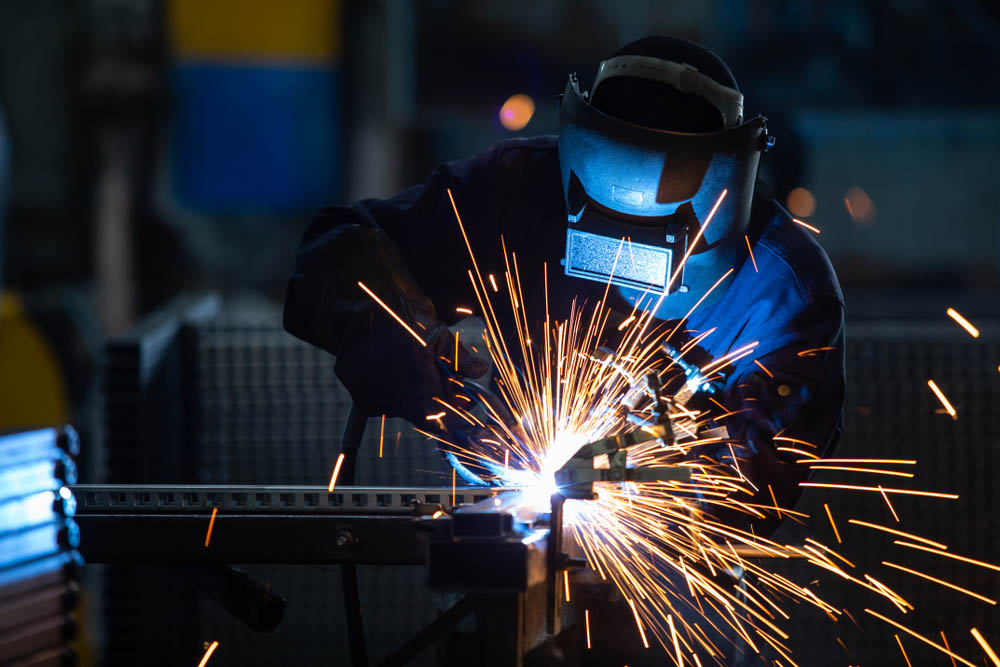 A welding technician joining two pieces of steel